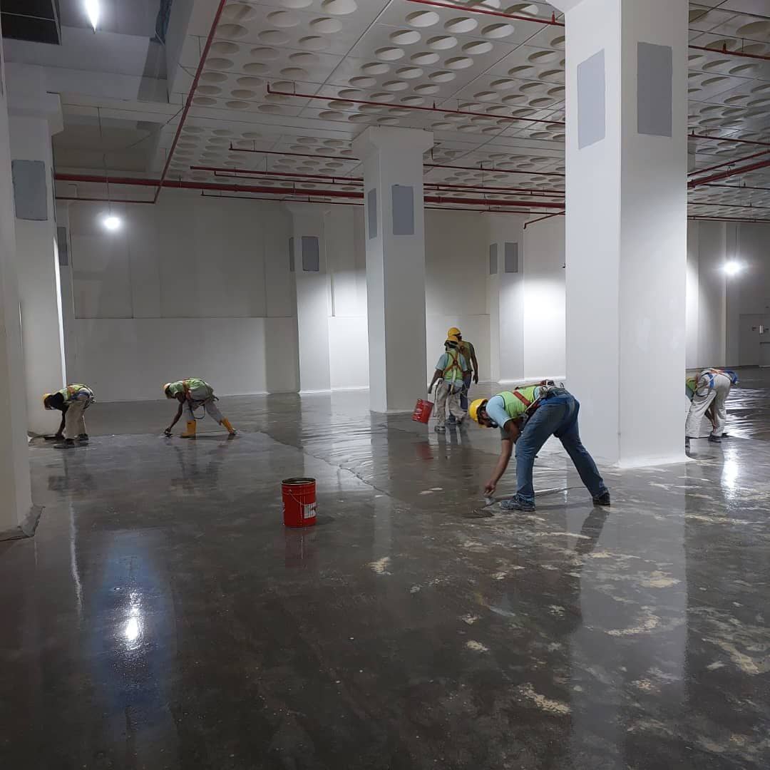 Crew priming warehouse concrete floor: primer/sealer on concrete, grey